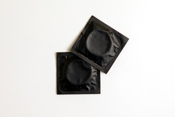 black condom on white background, top view, safe sex concept