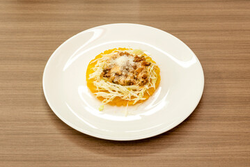 A beef enchilada with cheese and lettuce on a shiny white plate