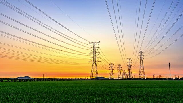 High voltage electric towers at sunrise. Transmission power line. Electricity pylons and sky clouds background.