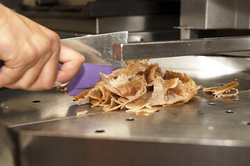 A kebab employee cutting roast lamb meat on the roll to prepare a sandwich