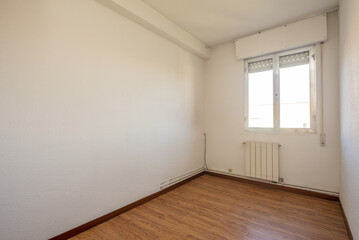 Empty living room of a house with emadra-like sintasol floors, a white aluminum radiator and a window with a blind