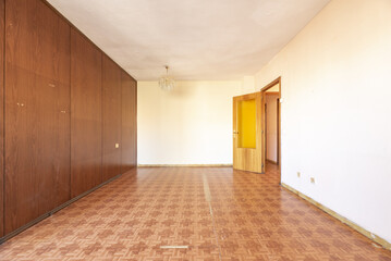 Empty living room of an old house with oak flooring and wood paneled walls