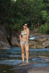 Obraz premium fit girl poses on a rock in a river in australia