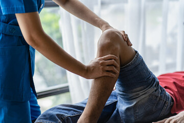 Young man with knee pain doing physiotherapy to rehabilitate leg for immobile patient Serious doctor helping male athlete exercise during rehabilitation after leg injury