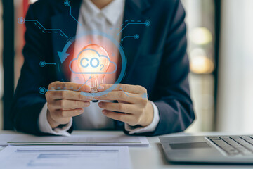 Businessman hand holding light bulb with natural energy icons, financial documents and tools for inspiration and creativity. Science innovation technology and communication network connection