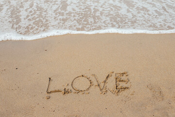 Love lettering on the sandy beach and sea water