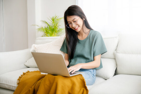 Smiling young asian woman working on laptop at home. Attractive asia female using computer remote studying, watching online education and video calling
