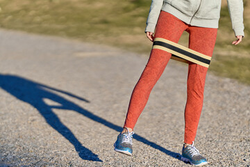 view of woman legs stretching outdoors in red leggings