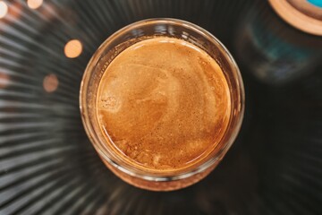 Close up dirty coffee in transparent glass served on black tray in the cafe.