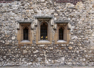 Fototapeta na wymiar Ancient worn down stone facade around some windows of the Westminster School in London, dating from the middle ages