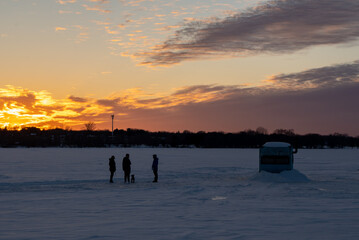 Winter socializing by ice fishing hut on frozen lake, Ontario Canada