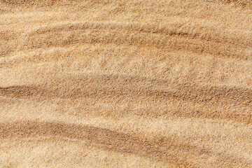 Wavy yellow sand texture closeup background, sandy waves pattern, natural beige sand grains backdrop, rippled dry sand surface top view, light orange desert dune, summer tropical sea beach, copy space