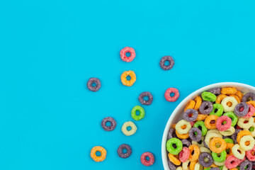 Colored breakfast cereal in a bowl on a blue background, flat lay, children's healthy breakfast, close up.