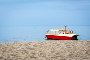 Red and white color speed boat on the beach, copy space.