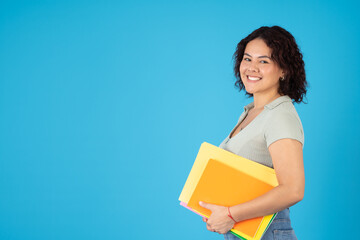 Young female student smiling with her colorful folders and notebooks
