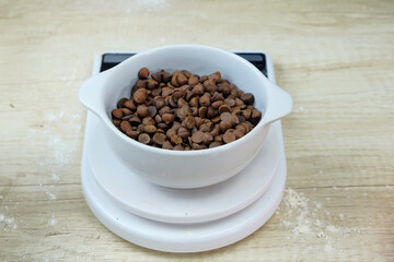 Fototapeta na wymiar Chocolate chips in the kitchen weighing bowl. Measuring cake ingredients