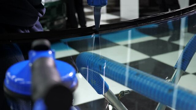 Automobile glazier adding glue on windscreen or windshield of a car in auto service station garage before installation. Repair and install auto glass.