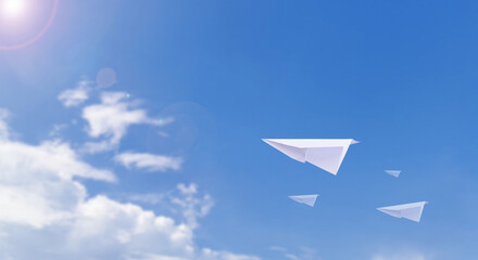 Naklejka na ściany i meble A paper airplane is flying in the beautiful clear sky.