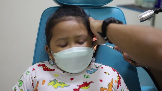 A child's ear is being examined by a doctor