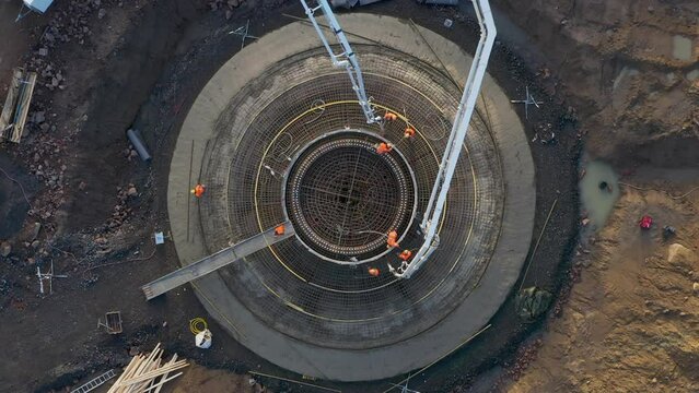 Pouring concrete in the footing foundation of a wind turbine during the construction, top down view of concrete casting with a concrete pump