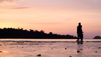 Fototapeta premium Young couple walking on the beach during sunset