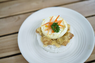 Salted egg dory fish rice. Spicy fried seafood fish shrimp squid with topping crispy egg and carrot pieces in plate