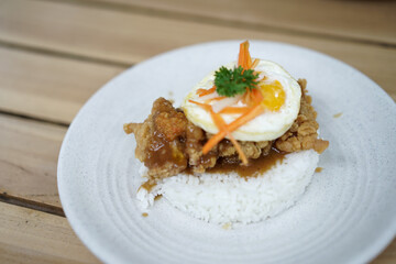 Spicy Chicken Rice garnished with egg and carrot pieces on a wooden table. Asian cuisine dishes for breakfast, dinner, or lunch.