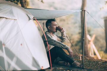 Man playing drink coffee in the morning during a camping trip in the forest on holiday. Vocation...