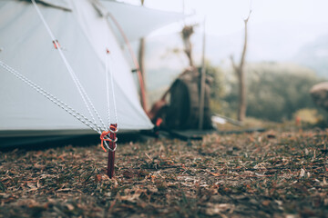 Naklejka premium Gray tent on the grass in the forest The view behind is the mountain in the morning. Camping, Travel and holiday concept.