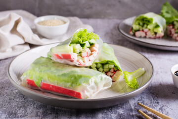 Vegetarian spring rolls with cucumber, crab sticks and lettuce on a plate on the table.