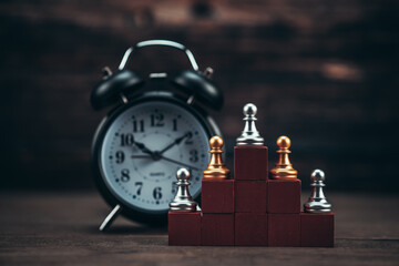 Alarm clock and chess piece on wood cube for ideas, challenge, leadership, strategy, business,...