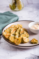 Fried pickles and sauce on a plate. American snack. Vertical view