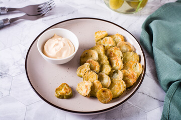 Fried pickles appetizer and sauce in a bowl on a plate. Homemade snack.