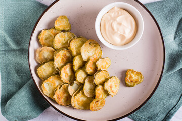 Fried pickles and sauce on a plate. American snack. Top view. Closeup
