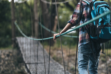 Hikers use trekking pole with backpacks and hold map walking through the bridge in the forest. hiking and adventure concept.