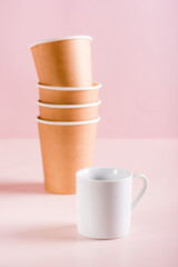 The concept of choosing between a ceramic and paper coffee cup. Reusable tableware. Vertical view
