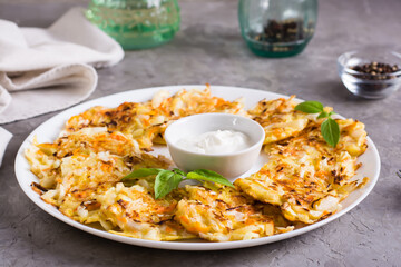Vegetable fritters from cabbage and carrots and sauce on a plate on the table. Vegetarian food.