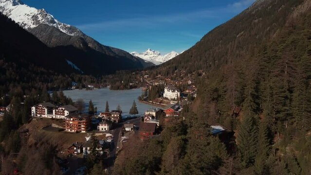 opening shot flying towards the lake champex lac in the swiss alpes. Stunning ice capped mountains in the background, close to mont blanc. Winter wonderland