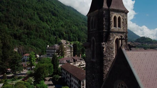 old stone catholic church of Interlaken in the swiss Alps. Aerial view pedestal up along the tower. revealing the township and Aere river
