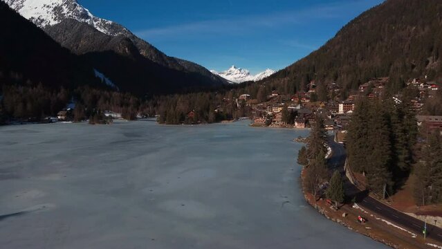 Flight over a frozen mountain lakes surrounded by ice capped mountains. Switzerland, lac champex in the swiss alpes