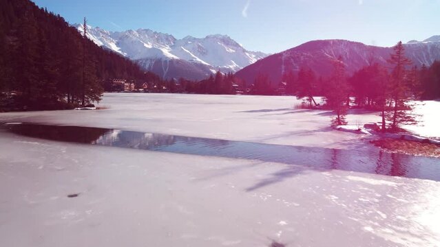low flight over the surface of a frozen lake in the swiss mountain. Opening shot of lac champex