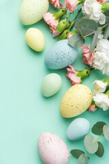 Naklejka na ściany i meble Easter colored eggs and a bouquet of white and pink carnations with eucalyptus branches on a soft green background.
