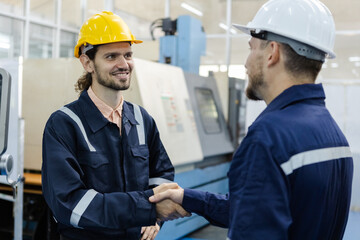 male engineers smiling wear helmets safety shake hands partner success at factory workshop. professional technician agreement plan production factory.