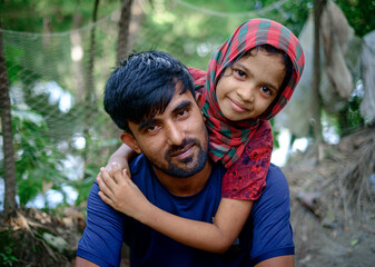 South asian father holding his daughter sitting outdoor park