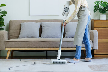 House wife with rechargeable vacuum cleaner cleaning at home