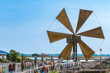 Wooden turbine at salt pan using for press seawater up to field with blue sky background in summer time of Thailand,South East Asia. Beautiful landscape of salt fields.Traditional salt farming culture