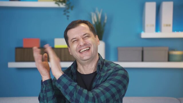 Funny and entertaining man clap at home smiling.
Smiling and clapping funny and having fun man enjoys good news.
