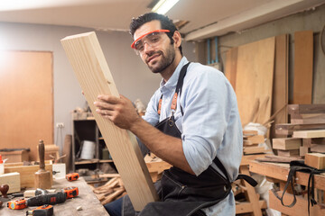 Carpenter man wearing glasses and working in wood workshop