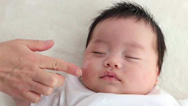 赤ちゃんの顔にクリームを塗るイメージ（0歳2か月、日本人、男の子）