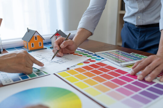 Graphic designers, architects, and painters are in a meeting to discuss how to sketch a structure. Finding a home-style color scheme that fits and matches the purpose of the client in the office.